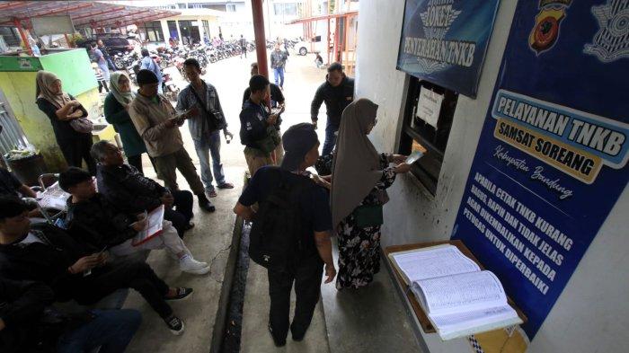 Warga yang setelah melakukan pembayaran pajak kendaraan bermotor (PKB) mengambil plat nomor di ruangan bagian belakang Kantor Samsat Soreang, Jalan Raya Gading Tutuka, Cingcin, Kabupaten Bandung, Jawa Barat, Rabu (9/4/2025).