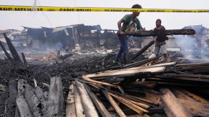Warga mengumpulkan kayu yang hangus terbakar di lokasi kebakaran, di Jalan Terusan Pasirkoja, Kelurahan Sukahaji, Kecamatan Babakan Ciparay, Kota Bandung, Jawa Barat, Kamis (10/4/2025).
