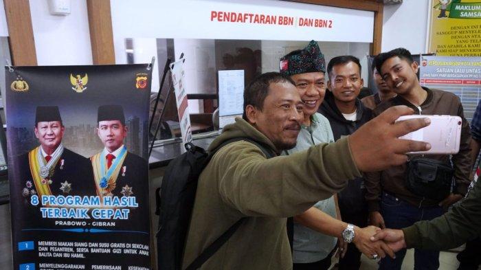 Bupati Bandung, Dadang Supriatna menyapa warga yang akan membayar pajak kendaraan bermotor saat melakukan inspeksi mendadak (sidak) di Kantor Samsat Soreang, Jalan Raya Gading Tutuka, Kabupaten Bandung, Jawa Barat, Jumat (11/4/2025).