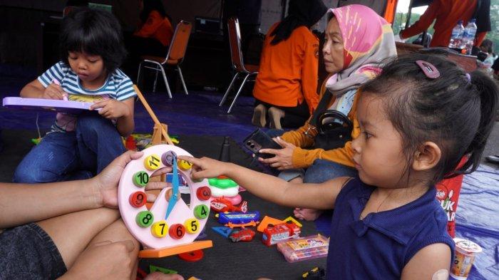 Anak kecil didampingi orang tuanya bermainan mainan di stand Badan Penanggulangan Bencana Daerah (BPBD) Provinsi Jawa Barat dalam gelaran Abdi Nagri Nganjang Ka Warga edisi pertama, di halaman Gedung Pakuan, Jalan Otto Iskandardinata, Kota Bandung, Jawa Barat, Sabtu (12/4/2025).