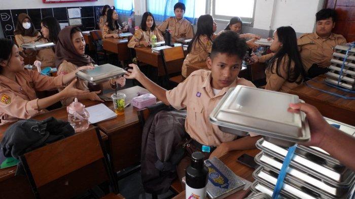 Pelajar membagikan makan bergizi gratis (MBG), di SMAN 20, Jalan Citarum, Kota Bandung, Jawa Barat, Senin (14/4/2025).