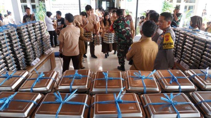 Petugas mendistribusikan makan bergizi gratis (MBG) kepada pelajar, di SMAN 20, Jalan Citarum, Kota Bandung, Jawa Barat, Senin (14/4/2025).