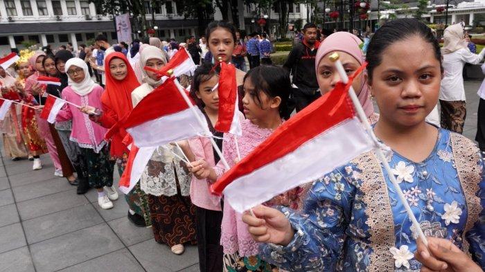 Sejumlah pelajar putri mengenakan kebaya mengibarkan bendera merah putih pada Peringatan Hari Kartini, di Plaza Balai Kota Bandung, Jalan Wastukencana, Kota Bandung, Jawa Barat, Senin (21/4/2025).