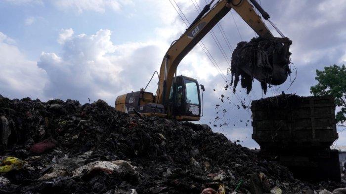 Petugas menggunakan alat berat beko memasukan sampah ke truk di Pasar Gedebage, Jalan Soekarno Hatta, Kota Bandung, Jawa Barat, Selasa (29/4/2025).