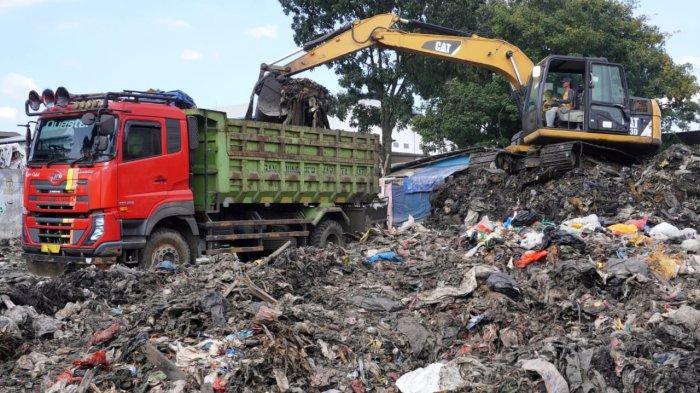 Petugas menggunakan alat berat beko memasukan sampah ke truk di Pasar Gedebage, Jalan Soekarno Hatta, Kota Bandung, Jawa Barat, Selasa (29/4/2025).