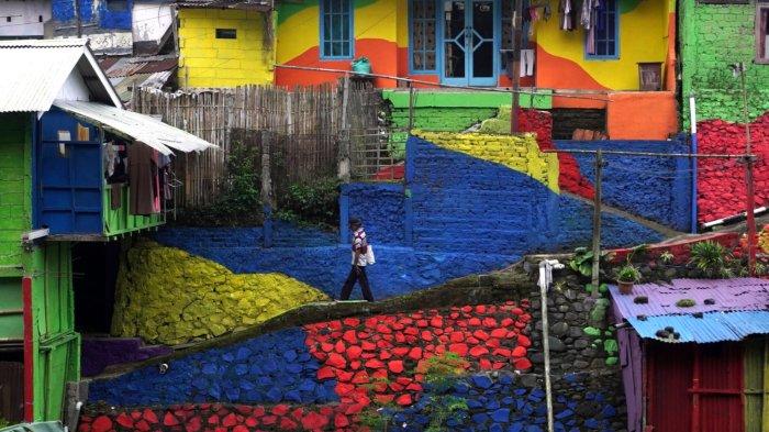 Warga melintas di kawasan permukiman yang dicat warna warni yang cerah, di Lembur Katumbiri, RW 12, Kelurahan Dago, Kecamatan Coblong, Kota Bandung, Jawa Barat, Selasa (6/5/2025).