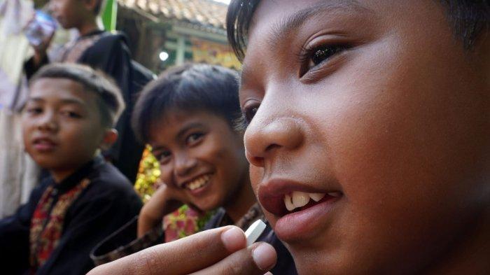 Seorang pelajar meminum obat cacing yang dibagikan secara gratis oleh petugas dari Puskesmas Rancamalaka Endah, di SDN Rancamanyar 3, Jalan Cilebak, Desa Rancamanyar, Kecamatan Baleendah, Kabupaten Bandung, Jawa Barat, Kamis (8/5/2025).