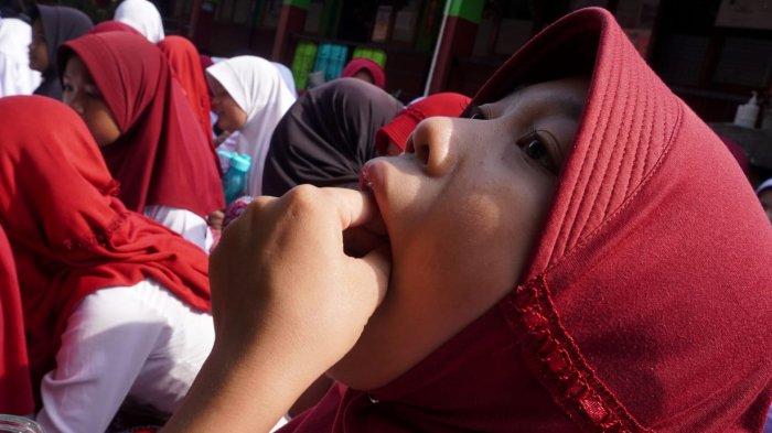 Seorang pelajar meminum obat cacing yang dibagikan secara gratis oleh petugas dari Puskesmas Rancamalaka Endah, di SDN Rancamanyar 3, Jalan Cilebak, Desa Rancamanyar, Kecamatan Baleendah, Kabupaten Bandung, Jawa Barat, Kamis (8/5/2025).