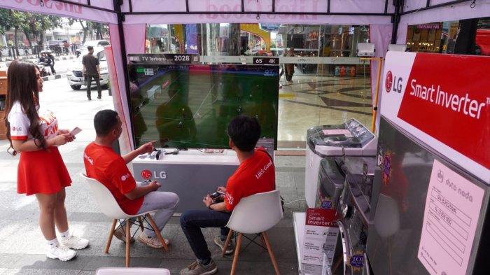 Dua orang petugas bermain game melalui televisi LG dengan layar besar pada gelaran kampanye Life's Good Truck di Bandung Indah Plaza (BIP), Jalan Merdeka, Kota Bandung, Jawa Barat, Jumat (9/5/2025).