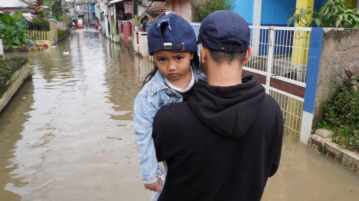 Warga melintasi banjir yang merendam jalan di Kampung Bojongasih, Desa/Kecamatan Dayeuhkolot, Kabupaten Bandung, Jawa Barat, Kamis (15/5/2025).