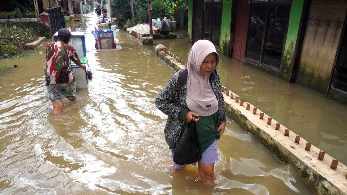 Warga melintasi banjir yang merendam jalan di Kampung Bojongasih, Desa/Kecamatan Dayeuhkolot, Kabupaten Bandung, Jawa Barat, Kamis (15/5/2025).