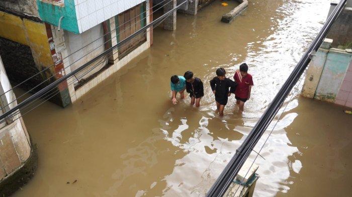Warga melintasi banjir yang merendam jalan di Kampung Bojongasih, Desa/Kecamatan Dayeuhkolot, Kabupaten Bandung, Jawa Barat, Kamis (15/5/2025).