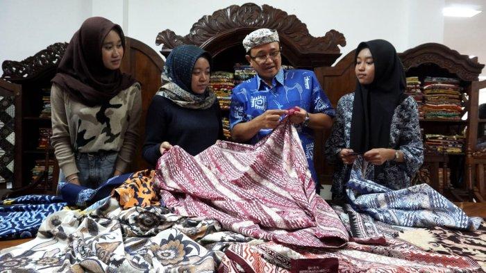 Pemilik Batik Komar, Komarudin Kudiya mengajak sejumlah mahasiswa yang melakukan kunjungan melihat kain batik yang desainnya hasil platform kecerdasan buatan/artificial intelegence (AI), di Kampung Batik AI Rumah Batik Komar, Jalan Cigadung Raya Timur, Kota Bandung, Jawa Barat, Senin (16/6/2025).