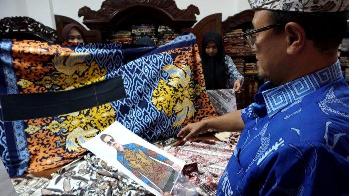 Pemilik Batik Komar, Komarudin Kudiya memperlihatkan gambar desain batik hasil platform kecerdasan buatan/artificial intelegence (AI) dengan yang sudah diaplikasikan pada kain, di Kampung Batik AI Rumah Batik Komar, Jalan Cigadung Raya Timur, Kota Bandung, Jawa Barat, Senin (16/6/2025).