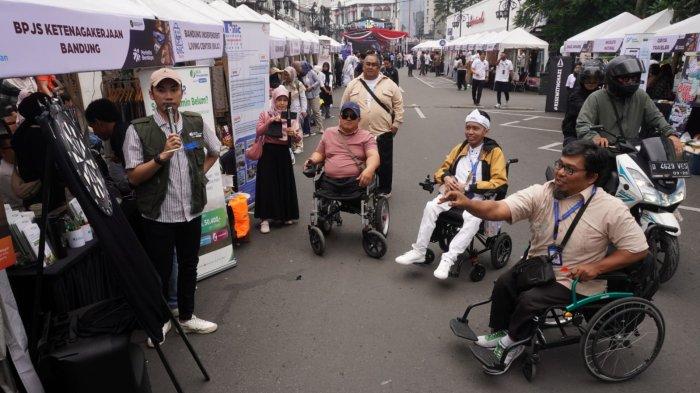 Pelaku UMKM disabilitas bermain lempar anak panah (dart) di stand BPJS Ketenagakerjaan Bandung pada gelaran Bazaar Berdaya Bersama 2025 di Jalan Braga, Kota Bandung, Jawa Barat, Sabtu (21/6/2025).