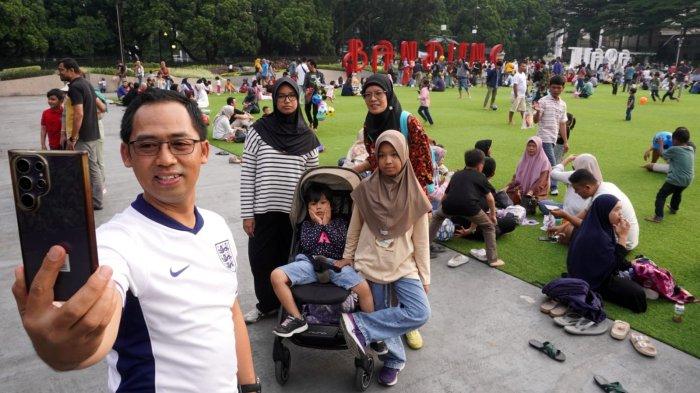 Warga mengisi liburan di lapangan rumput sintetis Taman Alun-alun Kota Bandung, Jawa Barat, Jumat (27/6/2025).