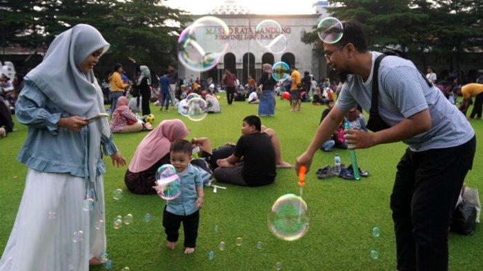 Warga mengisi liburan di lapangan rumput sintetis Taman Alun-alun Kota Bandung, Jawa Barat, Jumat (27/6/2025).