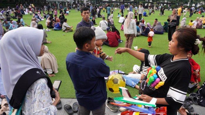Warga mengisi liburan di lapangan rumput sintetis Taman Alun-alun Kota Bandung, Jawa Barat, Jumat (27/6/2025).