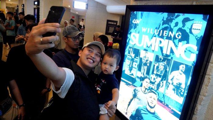 Bobotoh menggunakan ponselnya berswafoto di samping poster bergambar dua pemain anyar Persib Bandung untuk musim kompetisi Liga 1 2025/26 dan AFC Champions League Two 2025/26, yakni striker Ramon Tanque dan penjaga gawang Adam Przybek, di CGV Paris van Java, Kota Bandung, Jawa Barat, Sabtu (28/6/2025).