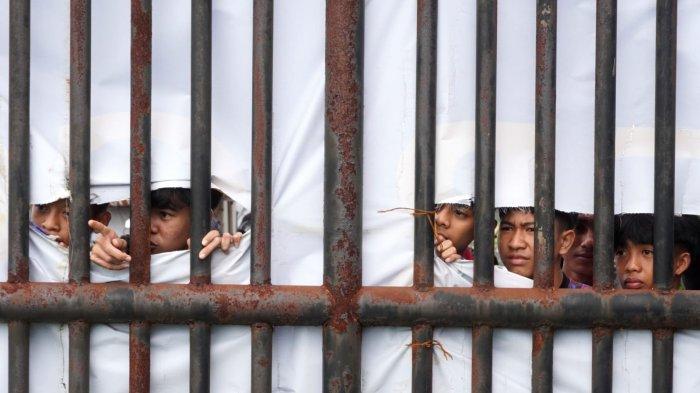 Sejumlah bobotoh dari balik banner penutup lapangan yang robel mengintip latihan perdana Persib Bandung di lapangan pendamping Stadion Gelora Bandung Lautan Api (GBLA), Kota Bandung, Jawa Barat, Senin (30/6/2025) pagi.