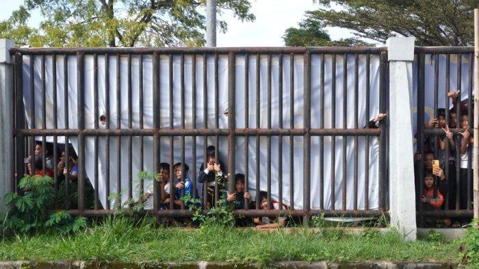 Sejumlah bobotoh dari balik banner penutup lapangan yang robel mengintip latihan perdana Persib Bandung di lapangan pendamping Stadion Gelora Bandung Lautan Api (GBLA), Kota Bandung, Jawa Barat, Senin (30/6/2025) pagi.