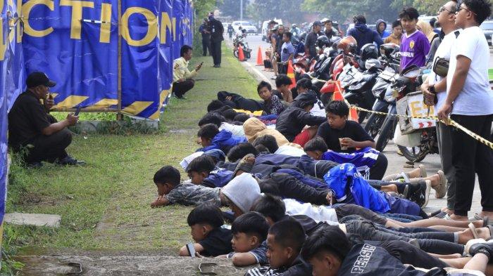 Sejumlah bobotoh cilik tiarap berjejer dari balik pagar yang ditutup banner mengintip pemain Persib Bandung menjalani latihan resmi di lapangan pendamping Stadion Gelora Bandung Lautan Api (GBLA), Gedebage, Kota Bandung, Jawa Barat, Sabtu (5/7/2025).