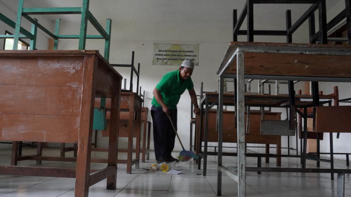 Petugas kebersihan menyapu salah satu ruang kelas yang sudah lama tidak diisi murid di Sekolah Menengah Kejuruan (SMK) Tamansiswa, Jalan Tamansiswa, Kota Bandung, Jawa Barat, Kamis (24/7/2025).