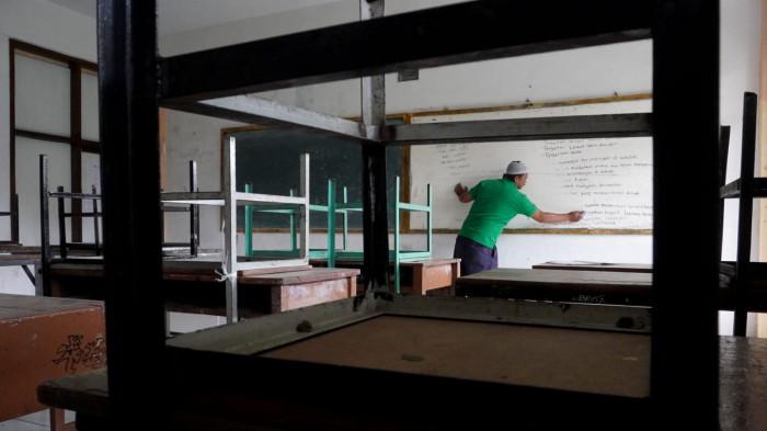 Petugas kebersihan membersihkan papan tulis di salah satu ruang kelas yang sudah lama tidak diisi murid di Sekolah Menengah Kejuruan (SMK) Tamansiswa, Jalan Tamansiswa, Kota Bandung, Jawa Barat, Kamis (24/7/2025).