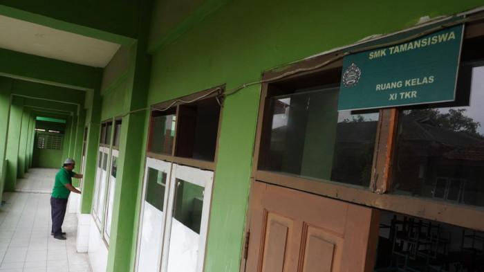 Petugas kebersihan menutup ruang kelas setelah dibersihkan di salah satu ruang kelas yang sudah lama tidak diisi murid di Sekolah Menengah Kejuruan (SMK) Tamansiswa, Jalan Tamansiswa, Kota Bandung, Jawa Barat, Kamis (24/7/2025).