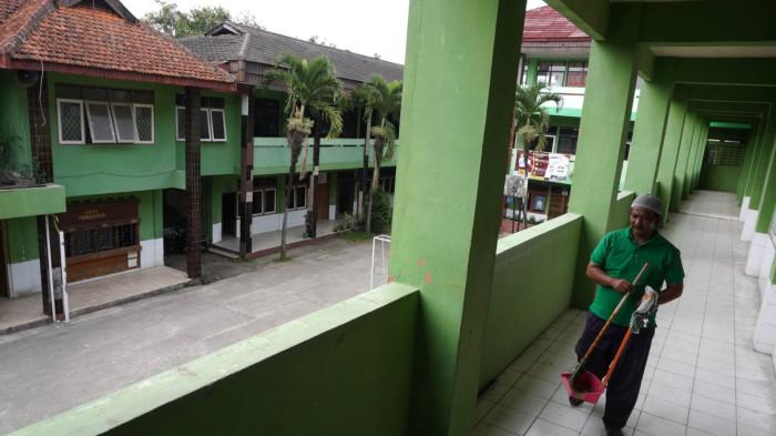 Petugas kebersihan meninggalkan ruang kelas dengan suasana sepi dan sunyi di Sekolah Menengah Kejuruan (SMK) Tamansiswa, Jalan Tamansiswa, Kota Bandung, Jawa Barat, Kamis (24/7/2025).