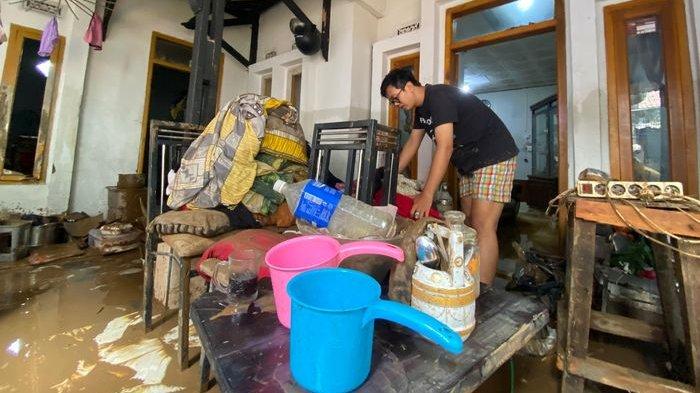 Anak Lina saat membereskan rumahnya yang terendam banjir di Banjaran.