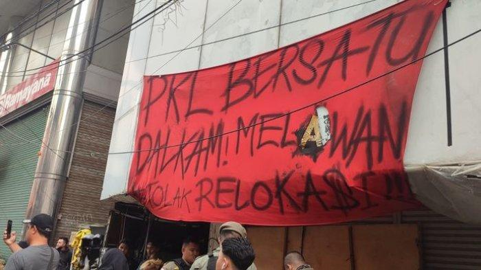 Spanduk berisi tolakan relokasi terpampang di Jalan Dalem Kaum, Kota Bandung. PKL dan Satpol PP sempat bentrok pada Jumat (22/12/2023). 