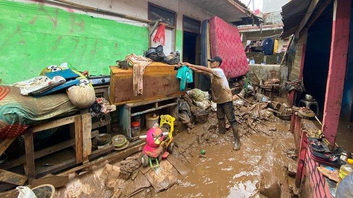 Nana Sumarna saat membersihkan rumahnya setelah diterjang banjir.