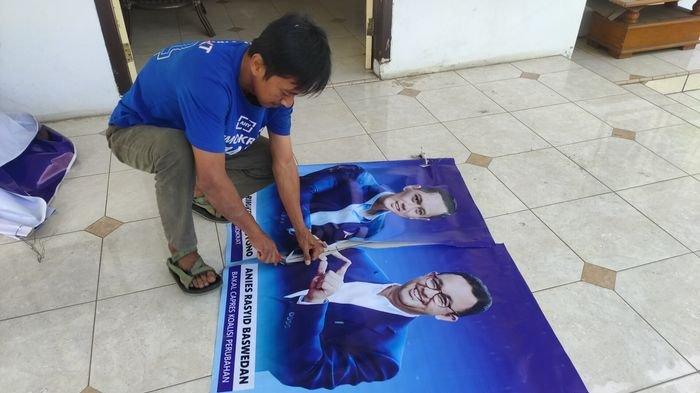 Seorang kader Demokrat di Kabupaten Cirebon sedang memisahkan foto AHY dan Anies dengan pisau, Jumat (1/9/2023).