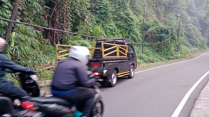 Seutas kabel listrik milik PT PLN melintang rendah di tengah jalan atas Cadas Pangeran, Kabupaten Sumedang. Tampak terpantau kabel itu melintang rendah setinggi atap mobil pikap saja, Jumat (18/7/2025). 