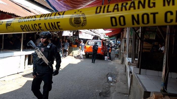 Petugas dengan senjata lengkap berjaga di lokasi olah tempat kejadian (TKP) penemuan mayat dalam karung di Pasar Cikurubuk Blok B1, Kota Tasikmalaya, Kamis (19/9/2024).