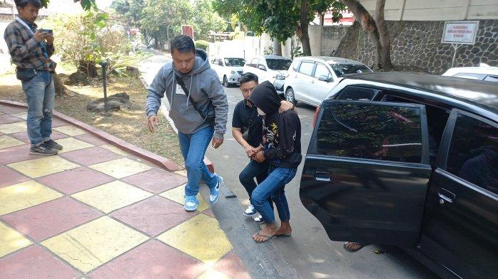 Pelaku penyiksa anak (diborgol) saat sampai di Satreskrim Polres Sukabumi