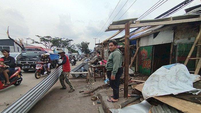 Pedagang di tepi Jalan Raya Rancaekek memperbaiki bangunan warungnya yang terkena angin puting beliung, Jumat (23/2/2024)