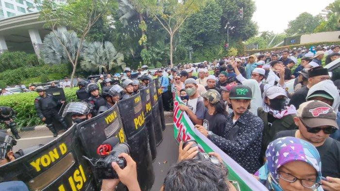 Massa penolak konser Coldplay  berhadapan dengan aparat Brimob bertameng saat mereka menggelar menggelar aksi di kawasan Senayan, Jakarta Pusat, Rabu (15/11/2023).