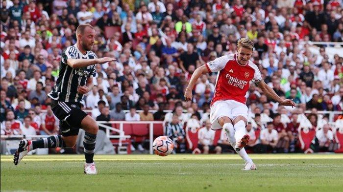 Gelandang Arsenal Martin Odegaard melakukan tembakan dihalau pemain manchester United Christian Eriksen di Stadion Emirates, Minggu (3/9/2023).