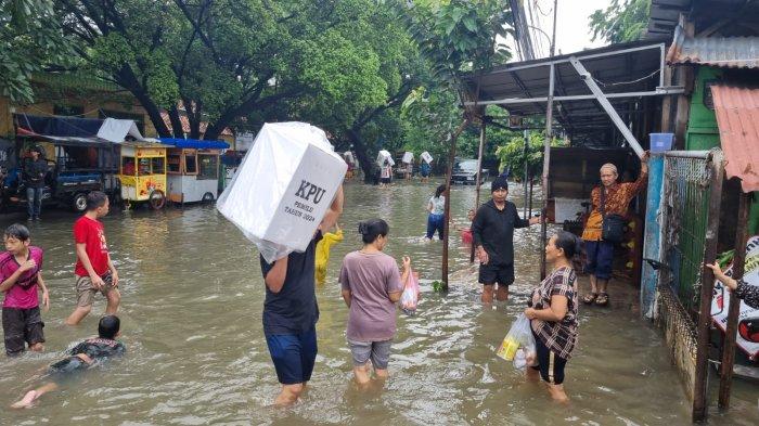 Petugas KPPS terpaksa menggotong logistik pemilu sambil menerobos banjir untuk dipindah dari TPS yang terendam banjir di RW 02 Patra, Duri Kepa, Kebon Jeruk, Jakarta Barat.
