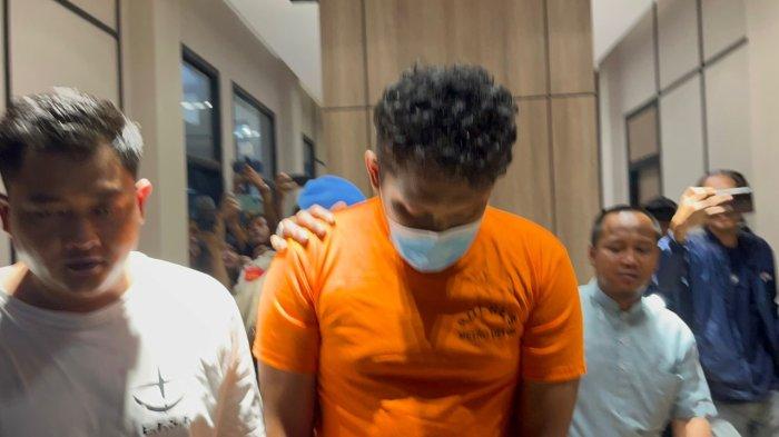 Polisi menggiring RAR (23), tersangka kasus penganiayaan dan pembunuhan orang tua, di Polsek Cimanggis, Kota Depok, untuk menjalani pemeriksaan pada Jumat (11/8/2023).