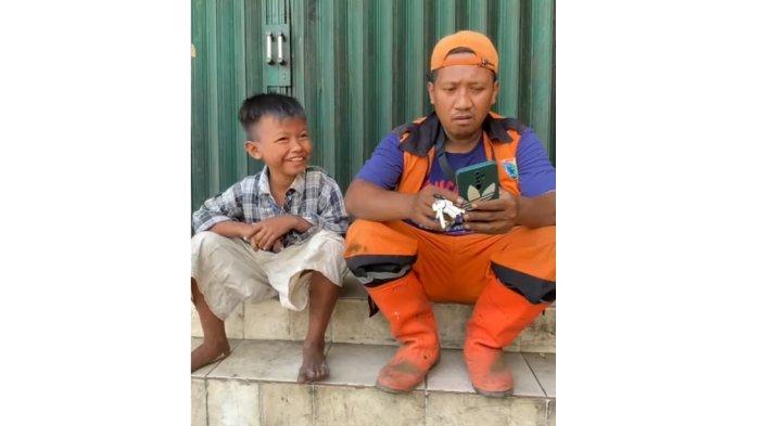 Senyuman K alias Awan (10), anak yang tewas dibanting ayahnya di Muara Baru, saat bercengkerama bersama petugas PPSU Penjaringan