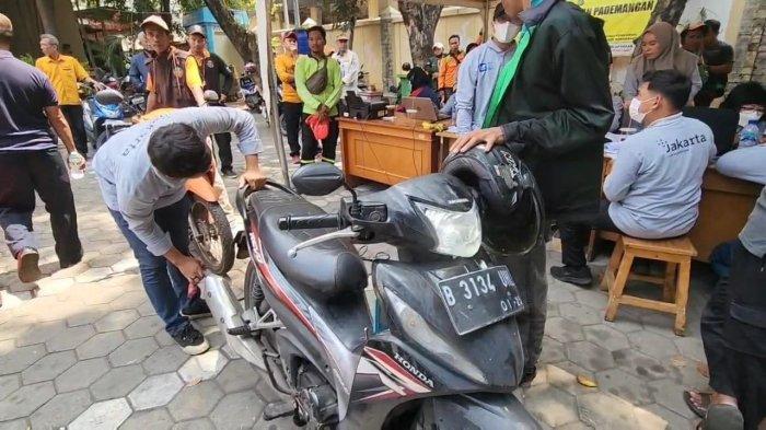 Seorang petugas Suku Dinas Lingkungan Hidup (LH) Jakarta Utara tengah melakukan uji emisi terhadap salah satau sepeda motor warga di kantor Kecamatan Pademangan.