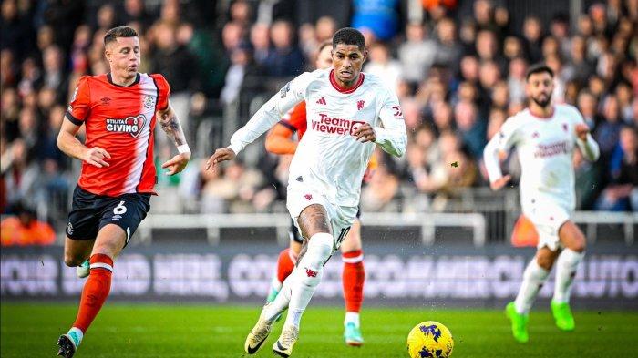 Striker Manchester United Marcus Rashford mengejar bola dari dan menghindar dari bek Luton Town di Liga Inggris.