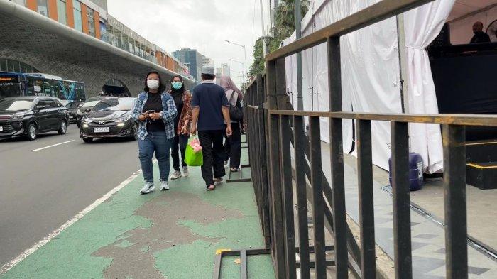 Sejumlah pejalan kaki terpaksa berjalan di ruas Jalan MH Thamrin karena akses trotoar yang tertutup total oleh tenda di sekitar kawasan Bundaran HI, Menteng, Jakarta Pusat, Sabtu (5/7/2025).