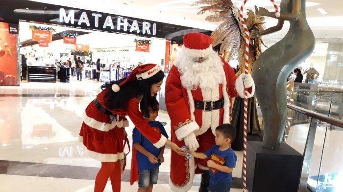 Santa Claus dan Santarina saat membagikan permen kepada pengunjung di Lippo Mall Kemang , Minggu (26/12/2018).