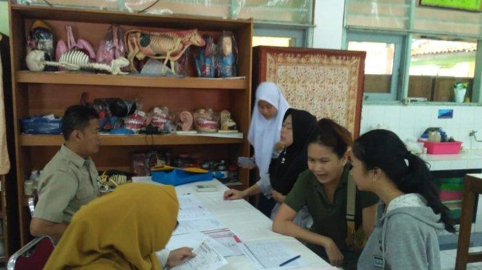 Sari (berkerudung hitam) dan anaknya (berkerudung putih) saat diberikan pengarahan dari pihak sekolah usai lapor diri di SMAN 78 Jakarta, Palmerah, Jakarta Barat (2019).