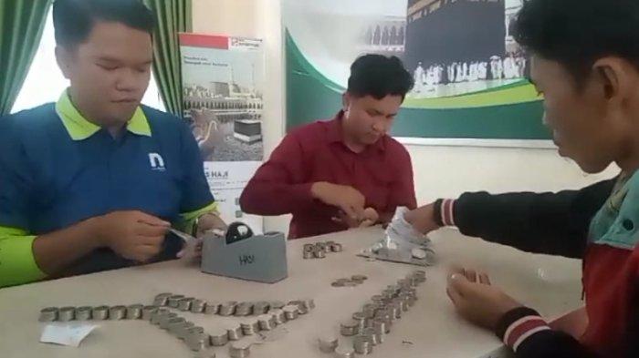 Petugas menghitung uang receh yang disetorkan Maryani untuk berangkat haji.