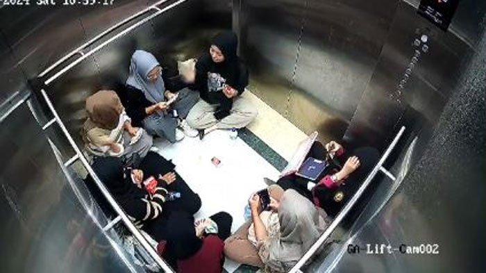 Potret 7 wanita terjebak di dalam lift. Mereka tampak santai duduk bersila sambil main kartu UNO.